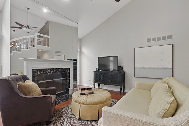 living room with hardwood / wood-style floors, high vaulted ceiling, ceiling fan, and a high end fireplace