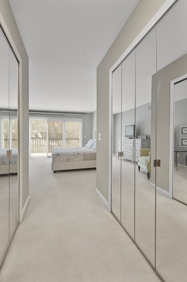 bedroom with two closets, light colored carpet, and multiple windows