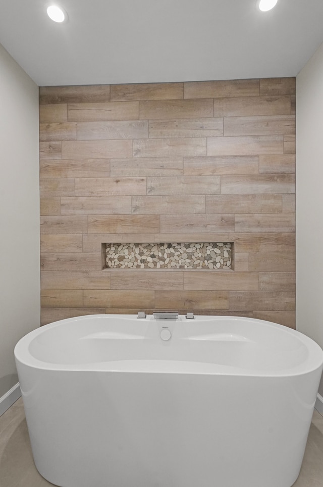 bathroom featuring a washtub and wood walls