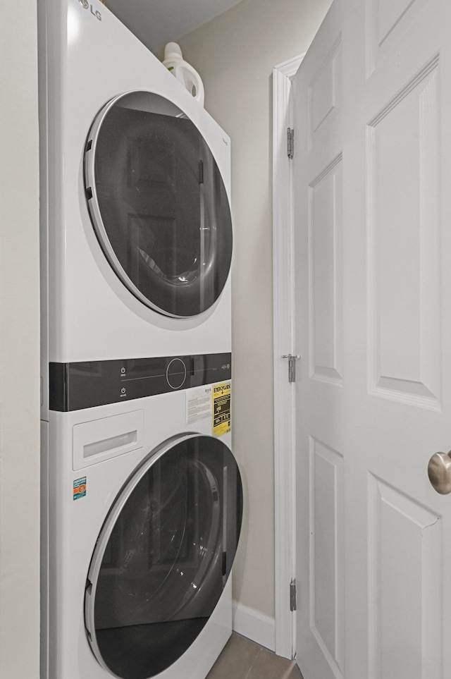 laundry room with stacked washing maching and dryer and light tile patterned floors