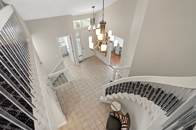 stairway with tile patterned flooring, a towering ceiling, and an inviting chandelier