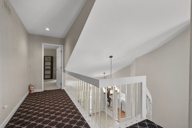 hallway featuring a chandelier, light colored carpet, and vaulted ceiling