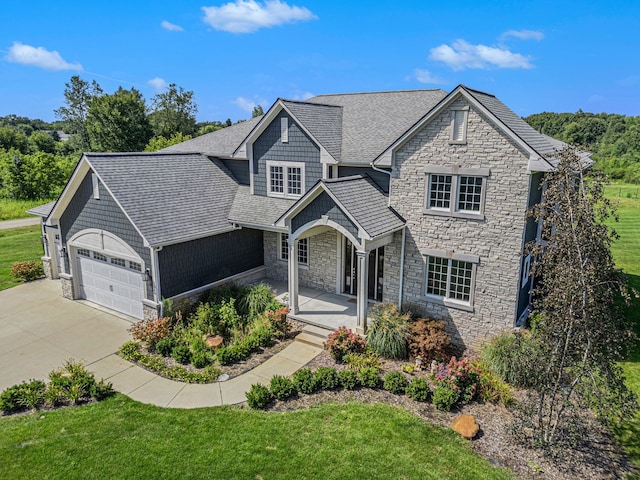 view of front of property featuring covered porch, a garage, and a front lawn