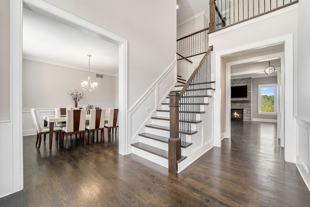 stairs with hardwood / wood-style flooring, a notable chandelier, ornamental molding, and a fireplace