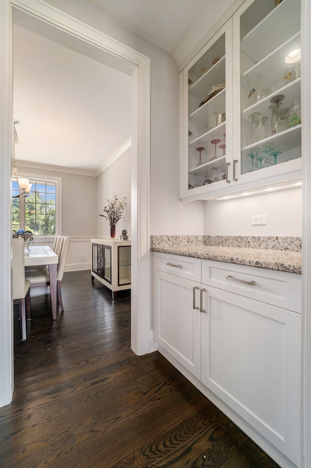 bar with white cabinets, crown molding, light stone counters, and dark wood-type flooring