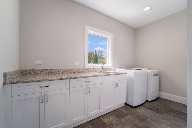 laundry area featuring washing machine and clothes dryer, cabinets, and sink