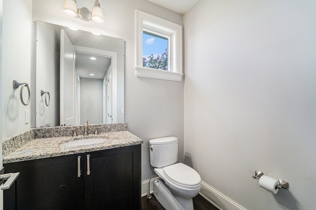 bathroom with wood-type flooring, vanity, and toilet