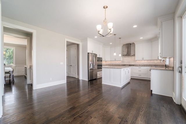 kitchen with pendant lighting, stainless steel refrigerator with ice dispenser, wall chimney exhaust hood, a kitchen island, and white cabinetry