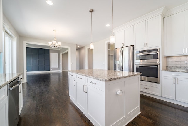 kitchen with pendant lighting, white cabinets, light stone countertops, tasteful backsplash, and stainless steel appliances