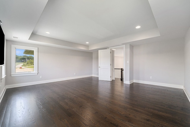 empty room featuring a raised ceiling and dark wood-type flooring