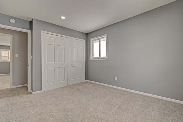 unfurnished bedroom with light carpet, a closet, and multiple windows