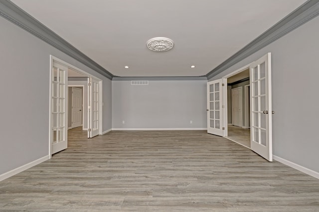 spare room with crown molding, french doors, and light wood-type flooring