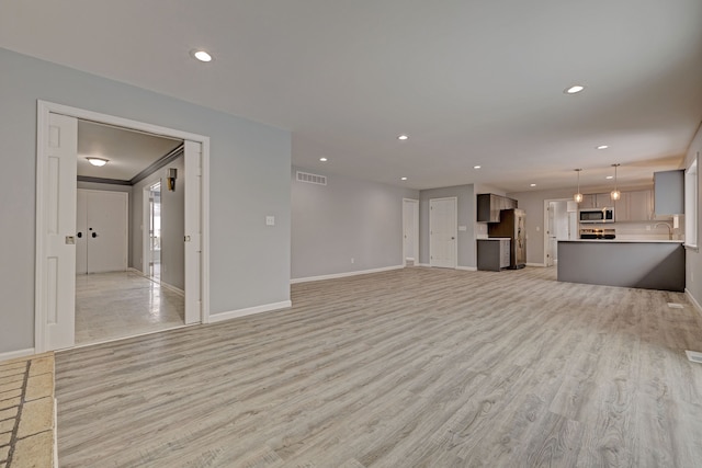 unfurnished living room featuring sink and light hardwood / wood-style floors