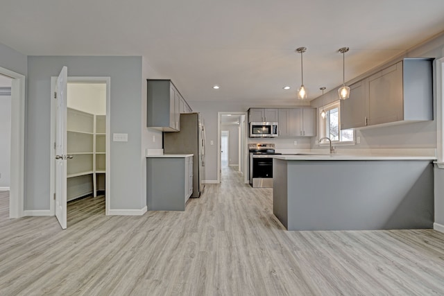 kitchen featuring sink, kitchen peninsula, light hardwood / wood-style floors, gray cabinets, and appliances with stainless steel finishes