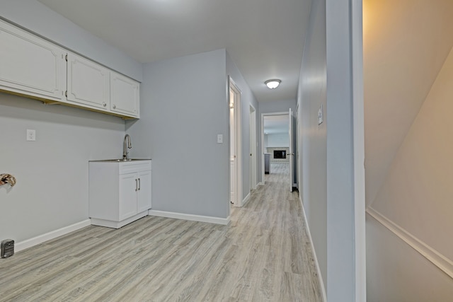 laundry room with light hardwood / wood-style floors and sink