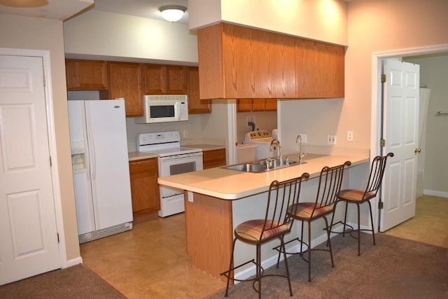 kitchen featuring kitchen peninsula, a breakfast bar, sink, and white appliances