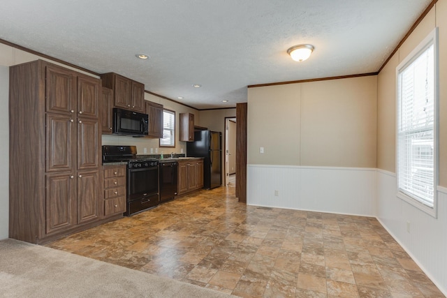 kitchen with a textured ceiling, black appliances, and crown molding