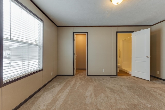 unfurnished bedroom with light carpet, a spacious closet, baseboards, and crown molding