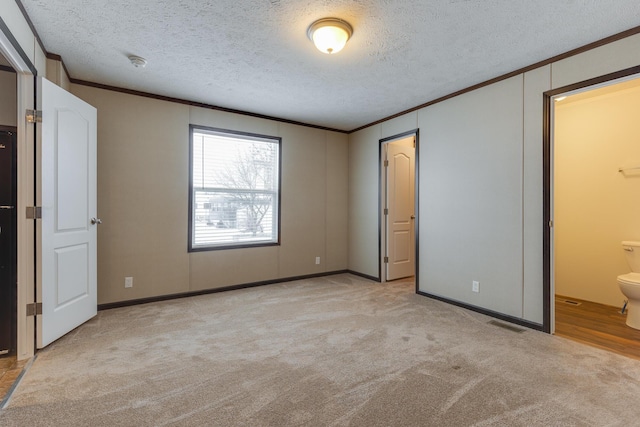 unfurnished bedroom with light carpet, a textured ceiling, crown molding, and connected bathroom