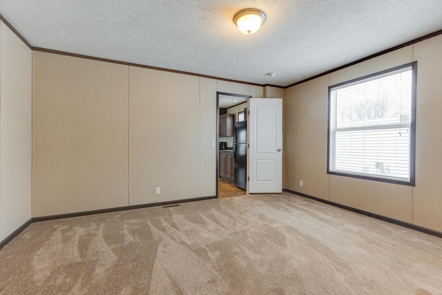 unfurnished room with crown molding, baseboards, light carpet, and a textured ceiling