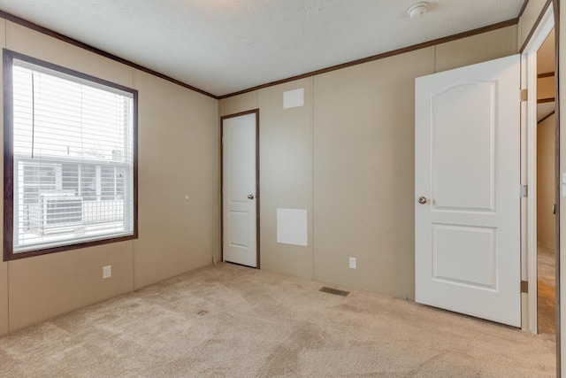 unfurnished bedroom with crown molding, carpet flooring, visible vents, and a textured ceiling