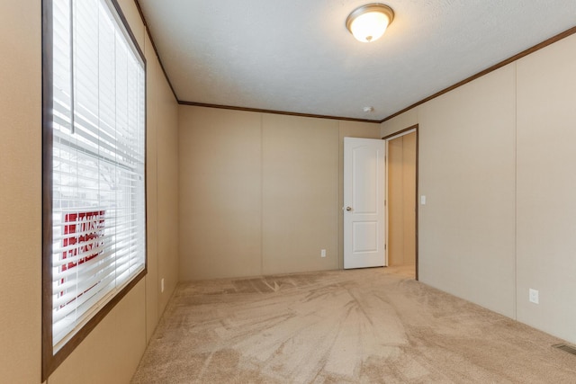 unfurnished room with light carpet, crown molding, and visible vents