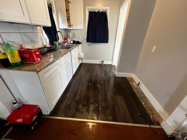 kitchen with dark wood-type flooring, sink, tasteful backsplash, dark stone counters, and white cabinets