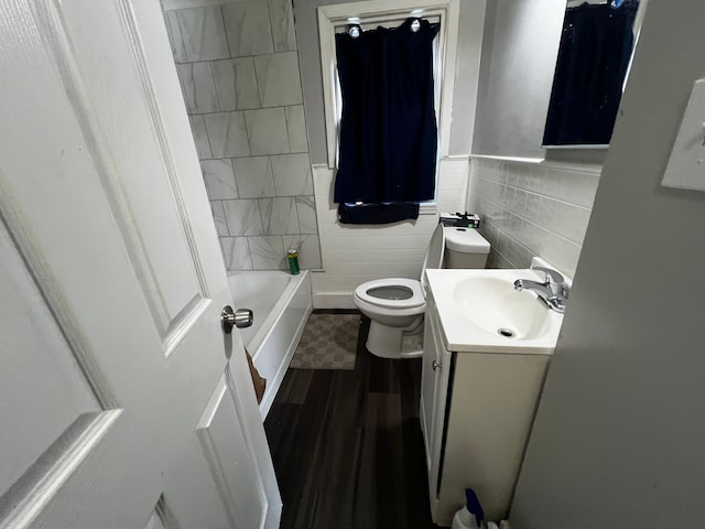 full bathroom with tile walls, hardwood / wood-style floors, vanity, toilet, and tiled shower / bath