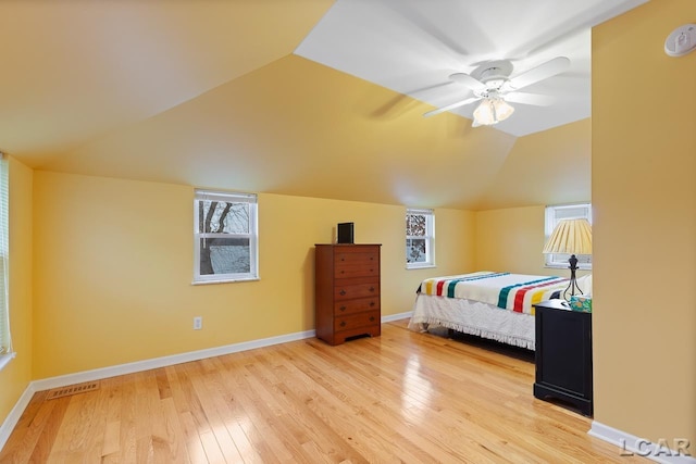 bedroom featuring multiple windows, ceiling fan, light hardwood / wood-style floors, and vaulted ceiling