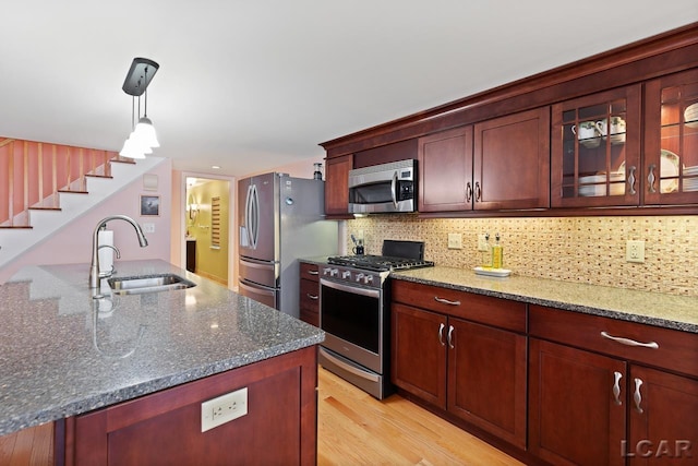 kitchen featuring appliances with stainless steel finishes, an island with sink, dark stone countertops, and sink