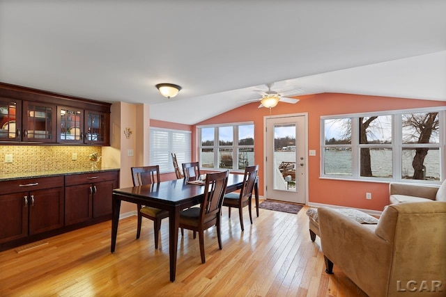 dining area with ceiling fan, light wood-type flooring, and vaulted ceiling