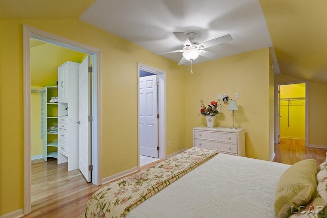 bedroom with ceiling fan, a spacious closet, light hardwood / wood-style flooring, vaulted ceiling, and a closet