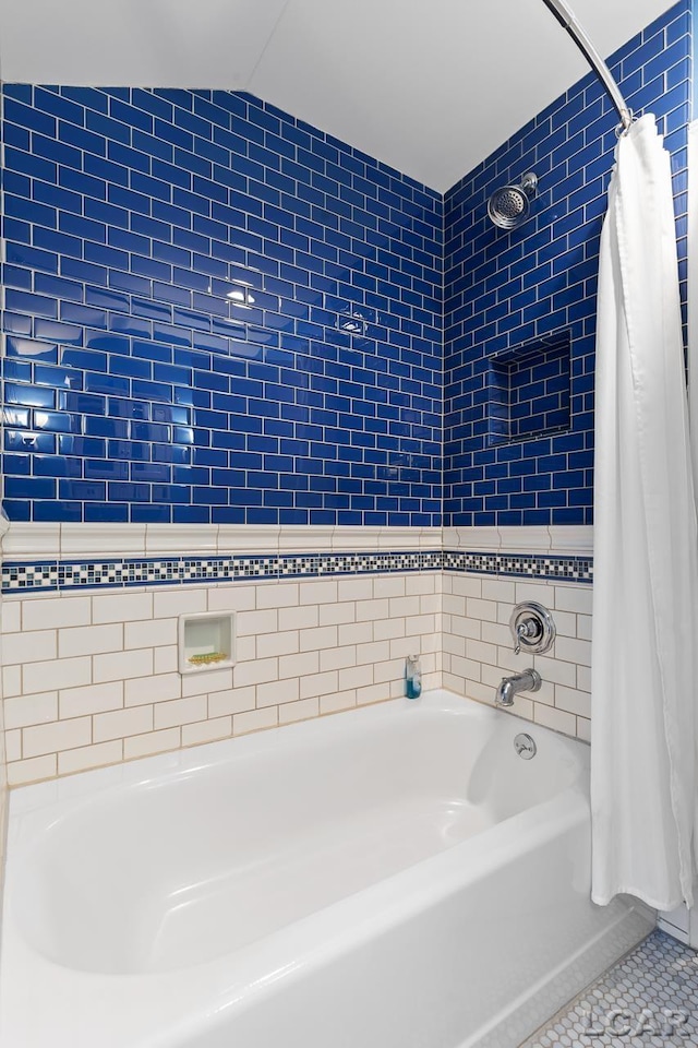 bathroom with tile patterned floors, lofted ceiling, shower / bathtub combination with curtain, and tile walls