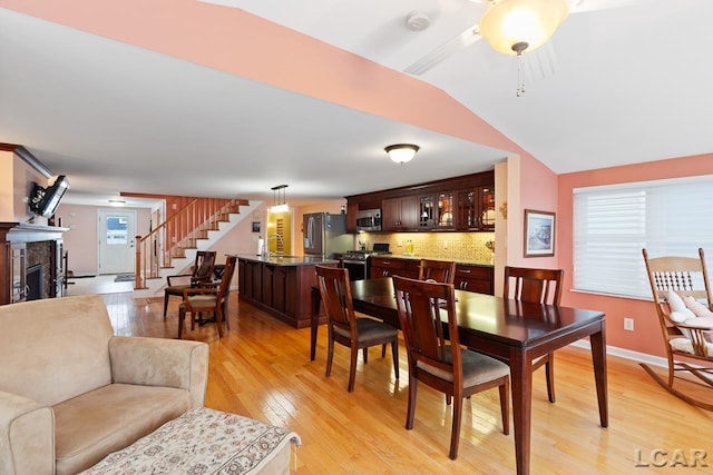 dining area with lofted ceiling, a wealth of natural light, and light hardwood / wood-style flooring