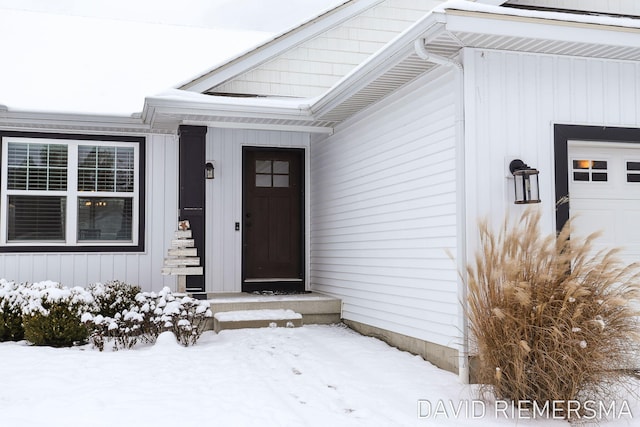 snow covered property entrance featuring a garage