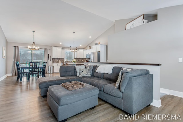 living room with high vaulted ceiling, light hardwood / wood-style floors, and a notable chandelier