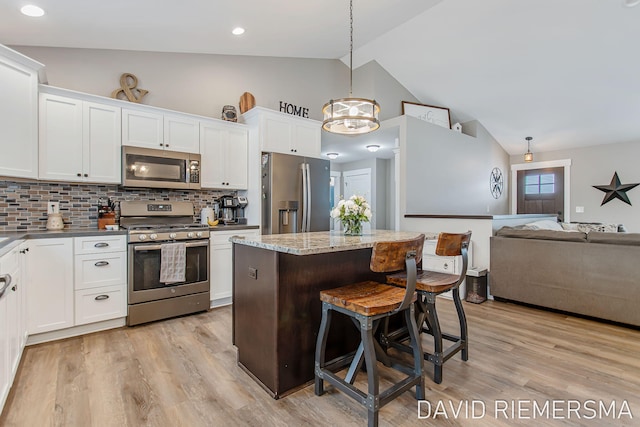 kitchen featuring white cabinetry, backsplash, stainless steel appliances, a kitchen island, and decorative light fixtures