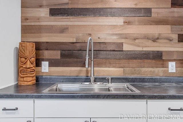 kitchen with wood walls, sink, and white cabinets