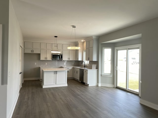 kitchen featuring stainless steel appliances, sink, a center island, dark hardwood / wood-style floors, and hanging light fixtures