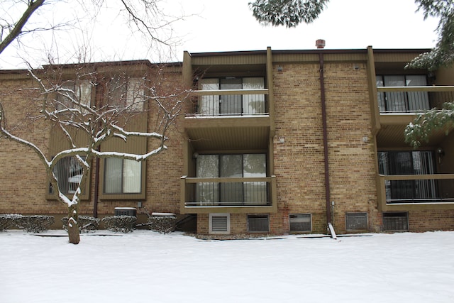 snow covered building with central AC unit