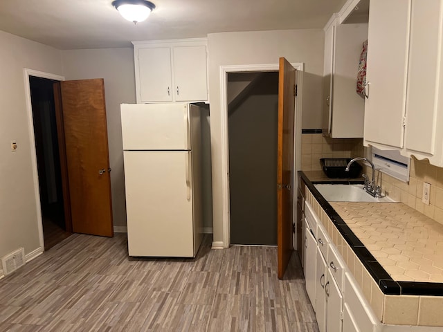 kitchen with tasteful backsplash, sink, white cabinets, white refrigerator, and tile counters