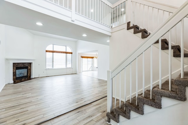 stairs with a high end fireplace, a high ceiling, and hardwood / wood-style flooring