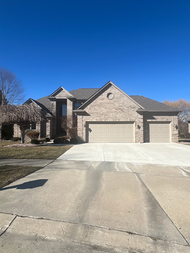 view of front of home with a garage, brick siding, roof with shingles, and concrete driveway