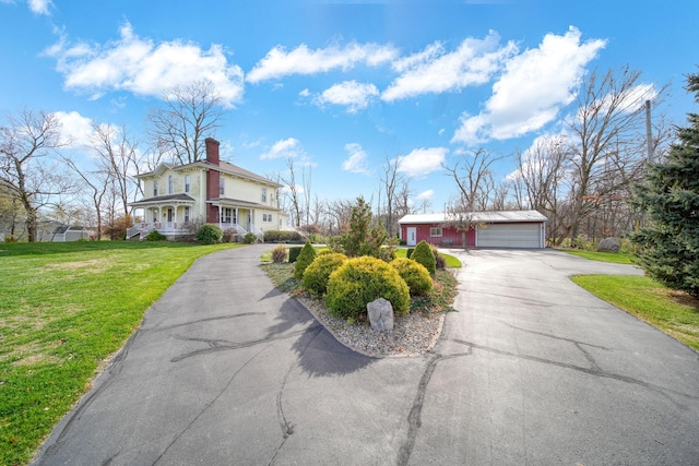 view of front of property featuring a garage, a front lawn, and an outdoor structure