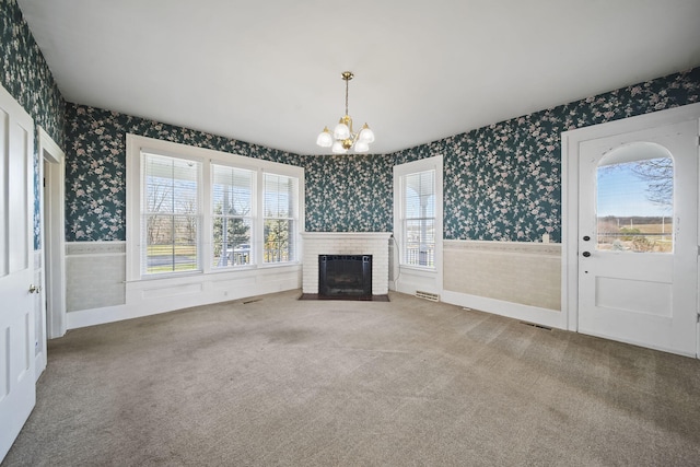 unfurnished living room with a fireplace, carpet, and an inviting chandelier