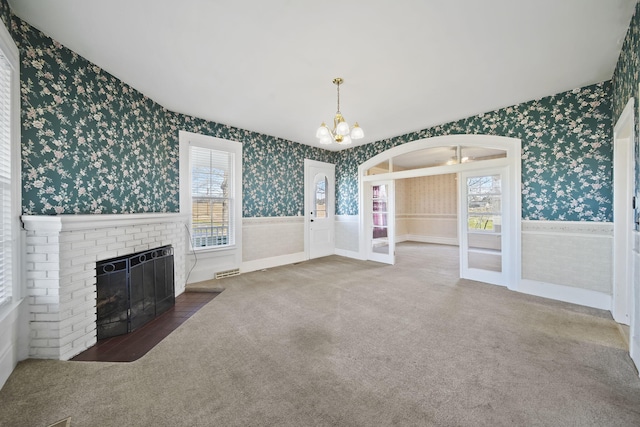 unfurnished living room featuring a fireplace, dark colored carpet, and a chandelier