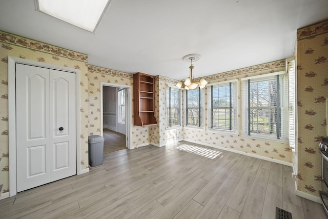 unfurnished dining area featuring light hardwood / wood-style flooring and a chandelier