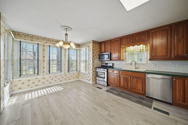 kitchen featuring a healthy amount of sunlight, sink, stainless steel appliances, and an inviting chandelier