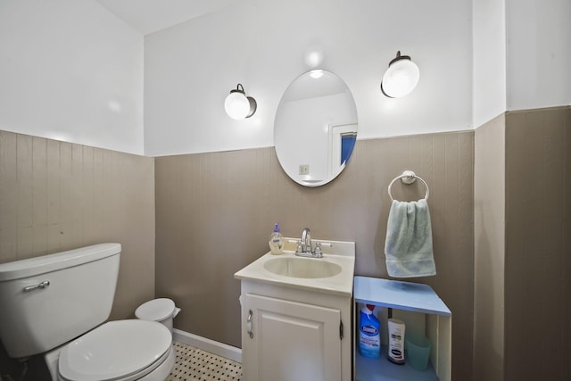 bathroom featuring wood walls, vanity, and toilet