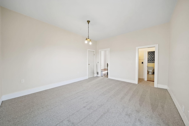 unfurnished room featuring light colored carpet and an inviting chandelier